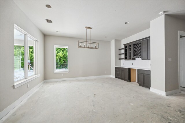 interior space with a chandelier, bar area, and baseboards