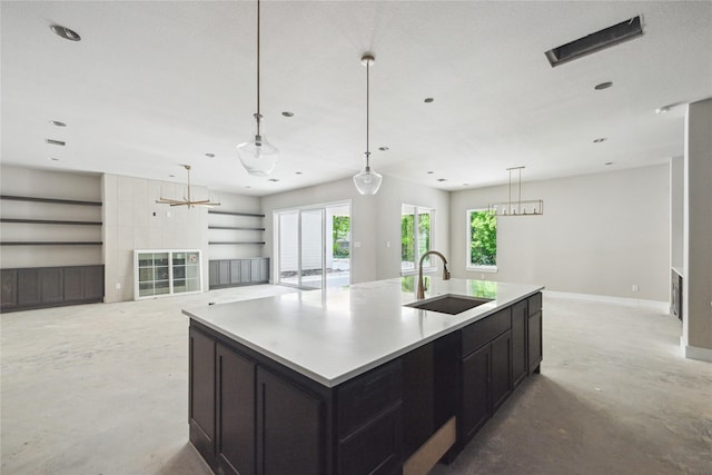 kitchen featuring a sink, a center island with sink, open floor plan, baseboards, and concrete floors