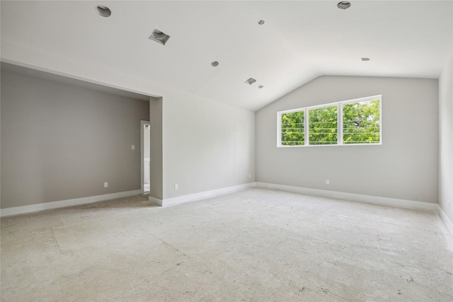 spare room featuring vaulted ceiling and baseboards