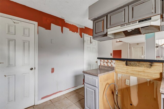 906 N Chamfer Way, Crosby, TX 77532 - kitchen with dark countertops, baseboards, under cabinet range hood, and light tile patterned floors