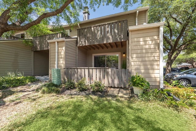 back of property with a chimney, a balcony, and fence