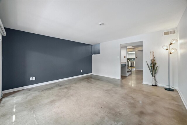 unfurnished living room with baseboards, visible vents, and finished concrete flooring