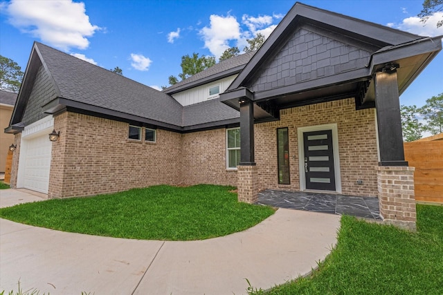 craftsman house featuring roof with shingles, an attached garage, a front yard, and brick siding