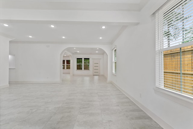 empty room with recessed lighting, arched walkways, and baseboards