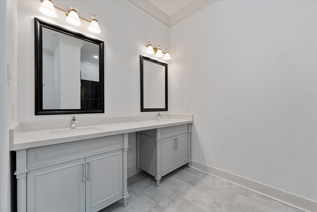full bath featuring double vanity, baseboards, and a sink