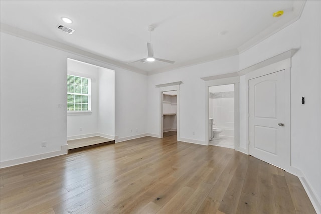 unfurnished bedroom with baseboards, a walk in closet, visible vents, and light wood-style flooring