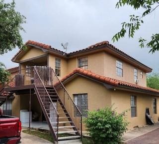view of front facade with stairs, stucco siding, and a tile roof