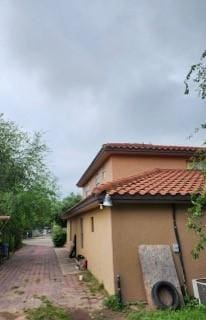 view of side of home featuring a tile roof and stucco siding