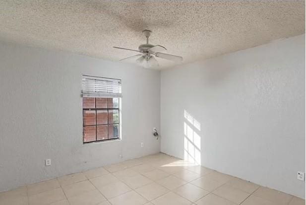 tiled spare room with a ceiling fan and a textured ceiling