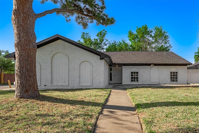 single story home with brick siding, roof with shingles, a front yard, and fence