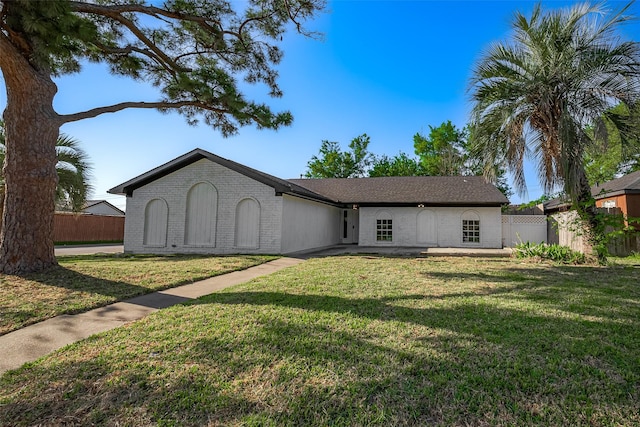 single story home featuring brick siding, fence, and a front yard