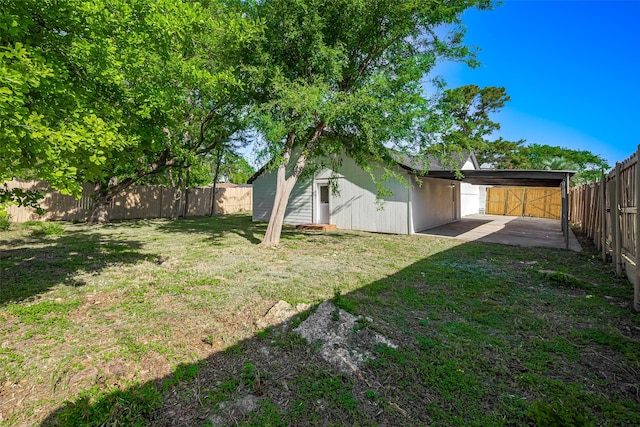 view of yard with a fenced backyard, a carport, and a patio
