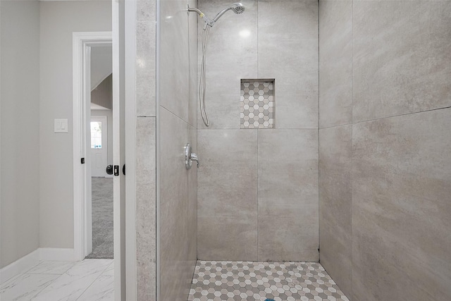 full bath featuring a tile shower, marble finish floor, and baseboards