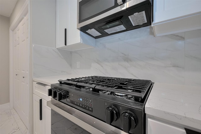 kitchen featuring white cabinets, gas stove, marble finish floor, and stainless steel microwave