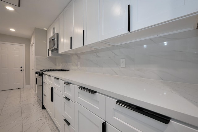 kitchen with recessed lighting, marble finish floor, light stone counters, appliances with stainless steel finishes, and white cabinetry