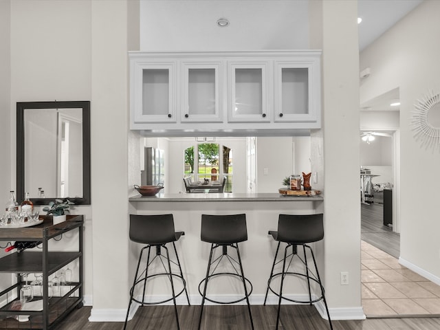 bar with a ceiling fan, baseboards, and tile patterned flooring
