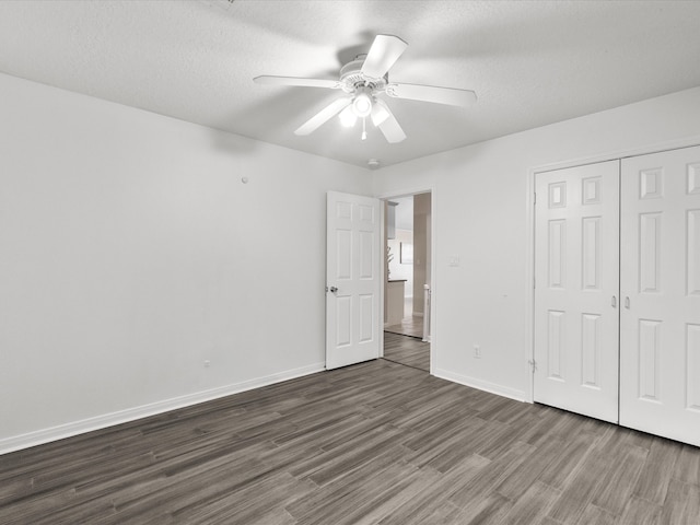 unfurnished bedroom featuring baseboards, a closet, ceiling fan, and dark wood finished floors