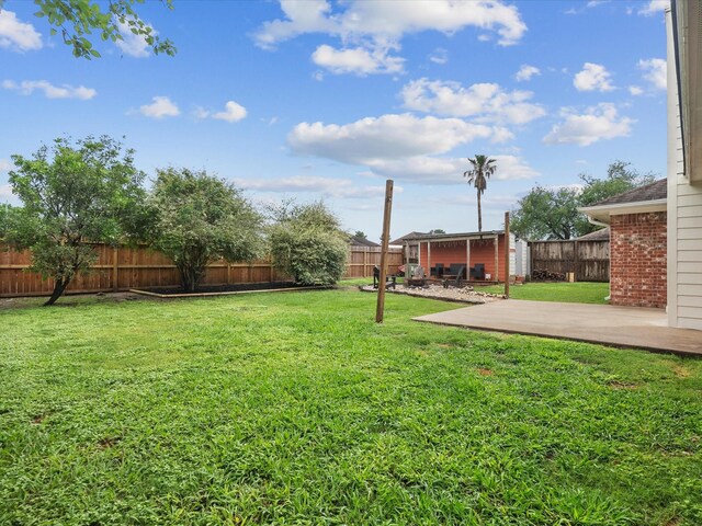 view of yard with a fenced backyard, an outdoor structure, and a patio