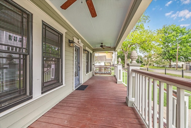 wooden terrace featuring a porch, ceiling fan, and fence