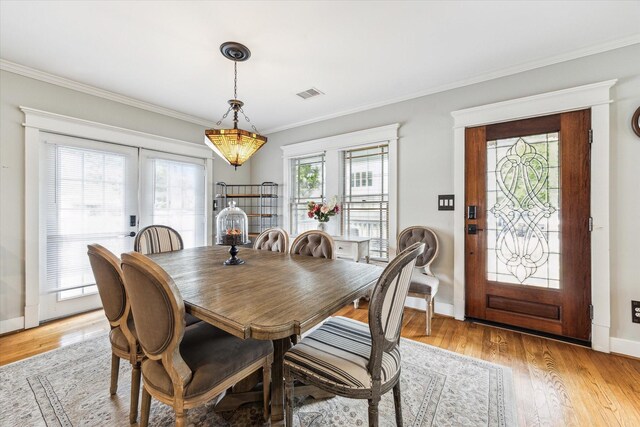 dining area featuring visible vents, ornamental molding, and light wood finished floors