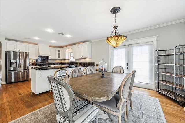 dining space featuring ornamental molding, french doors, wood finished floors, and visible vents