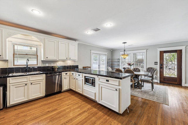 kitchen featuring visible vents, a peninsula, light wood-type flooring, a sink, and stainless steel appliances