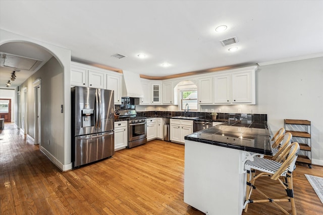 kitchen featuring a sink, white cabinets, custom exhaust hood, a peninsula, and stainless steel appliances