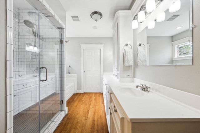 bathroom with vanity, a stall shower, wood finished floors, and visible vents