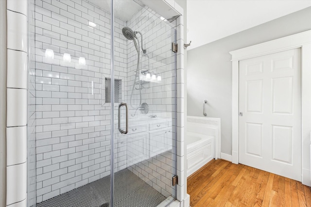 bathroom with a bath, wood finished floors, and a shower stall