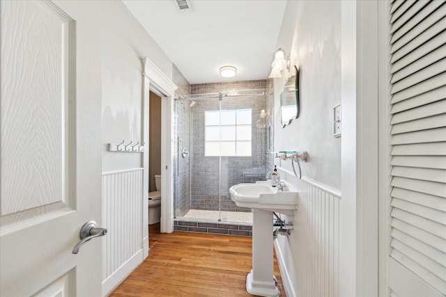 full bath featuring visible vents, wood finished floors, toilet, a wainscoted wall, and a shower stall