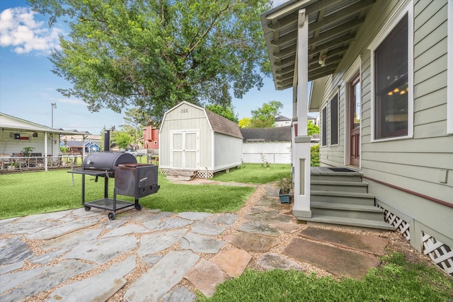 view of patio / terrace featuring a storage shed, fence, an outdoor structure, and area for grilling