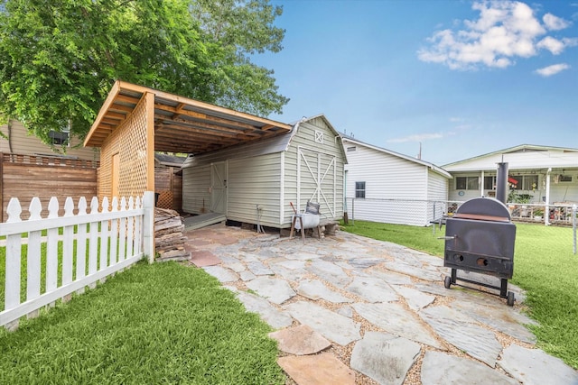 view of patio with fence, a storage unit, an outdoor structure, and a grill