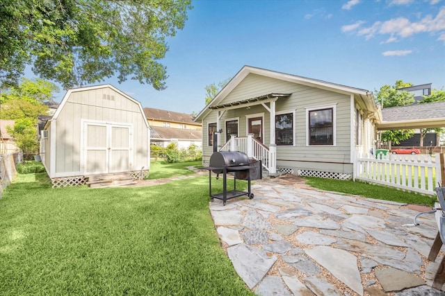 back of property with fence, a storage unit, an outdoor structure, a lawn, and a patio