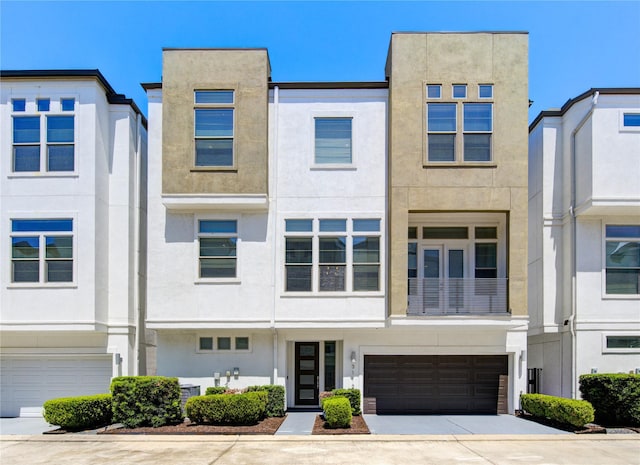 multi unit property with an attached garage, concrete driveway, and stucco siding