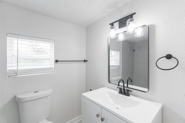bathroom featuring walk in shower, vanity, a textured ceiling, and toilet