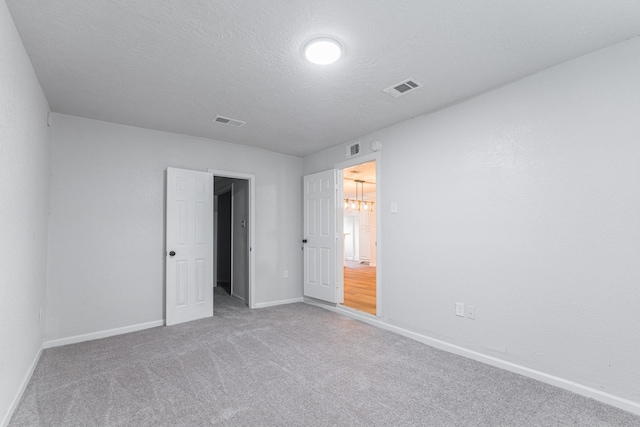 unfurnished bedroom with carpet floors, a textured ceiling, visible vents, and baseboards