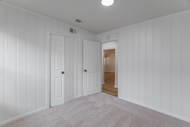 unfurnished bedroom featuring carpet, visible vents, and a closet