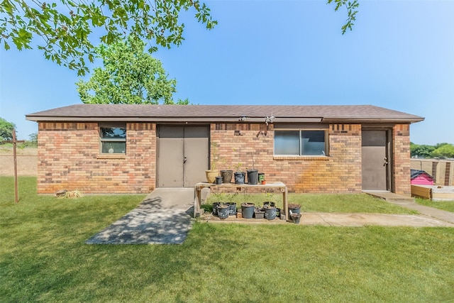 back of house featuring a lawn, brick siding, and a shingled roof