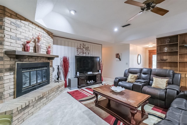 carpeted living room with a brick fireplace, visible vents, ceiling fan, and a tray ceiling