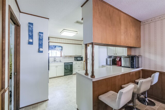 kitchen with black appliances, a peninsula, a textured ceiling, and wallpapered walls