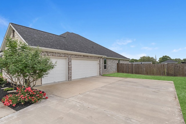 view of side of home with brick siding, a shingled roof, fence, and driveway