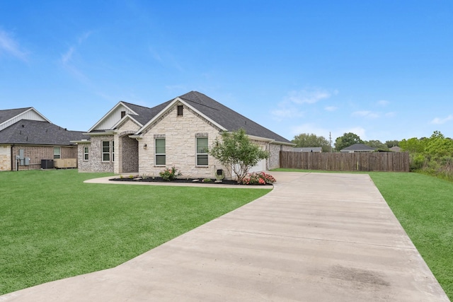 view of front facade featuring a front lawn, fence, stone siding, and concrete driveway