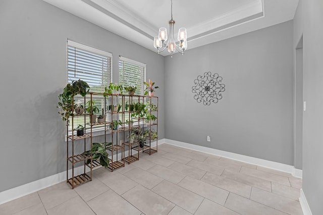 empty room with a tray ceiling, a notable chandelier, and baseboards