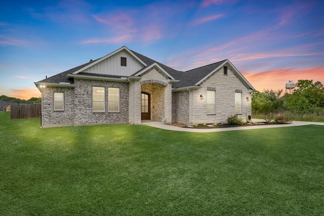 view of front of home featuring a lawn, fence, board and batten siding, and roof with shingles
