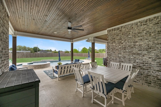 view of patio featuring an in ground hot tub, outdoor dining area, a fenced backyard, and ceiling fan