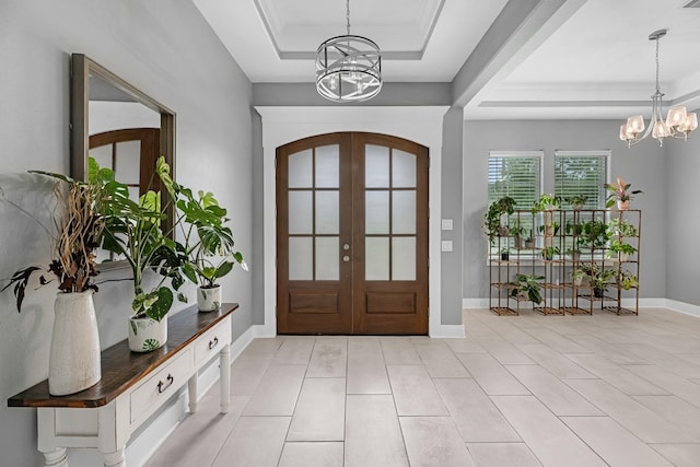 entryway featuring light tile patterned flooring, a tray ceiling, an inviting chandelier, and french doors