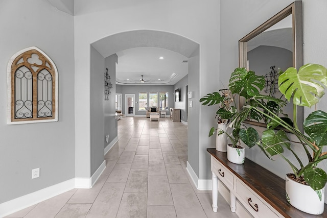 corridor with arched walkways, baseboards, recessed lighting, and light tile patterned floors