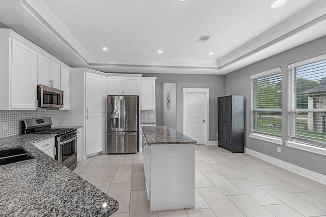 kitchen featuring appliances with stainless steel finishes, backsplash, a kitchen island, and a raised ceiling