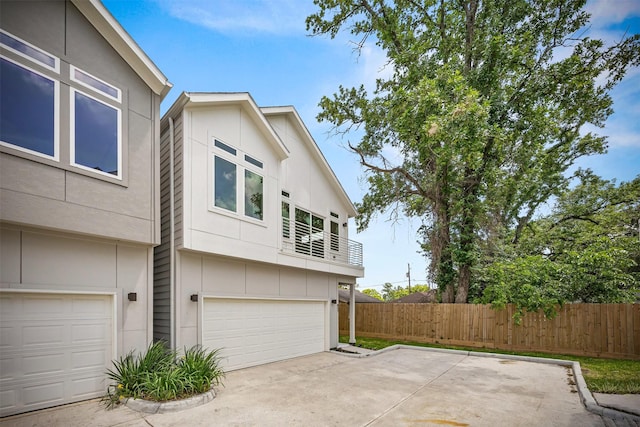 861 Prosper St, Houston, TX 77088 - view of property exterior featuring fence, a balcony, concrete driveway, an attached garage, and stucco siding
