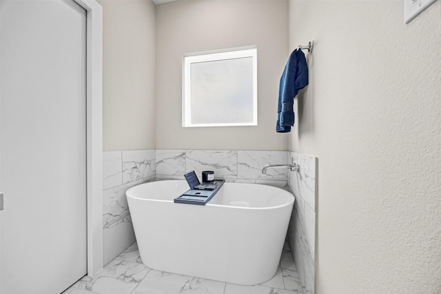 861 Prosper St, Houston, TX 77088 - bathroom featuring tile walls, a soaking tub, a wainscoted wall, and marble finish floor